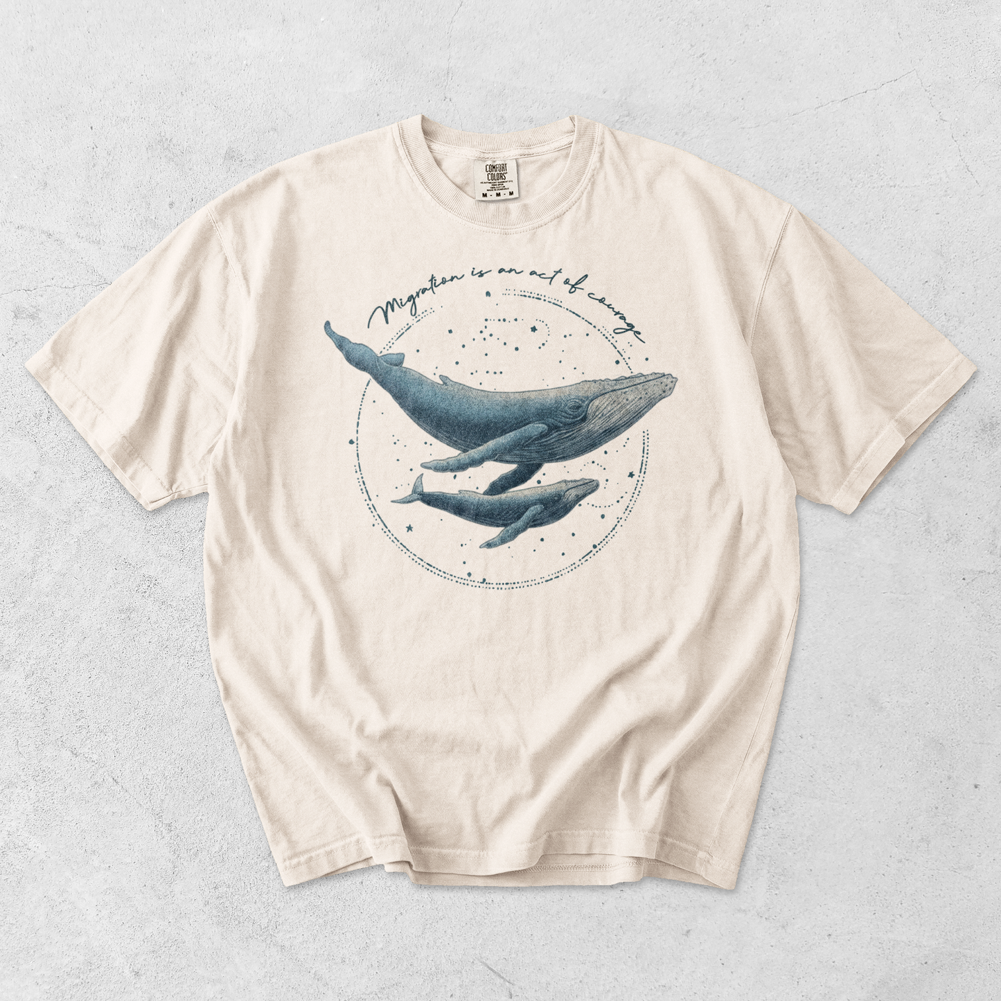 Ivory t-shirt with whale graphic with writing Migration is an Act of Courage
